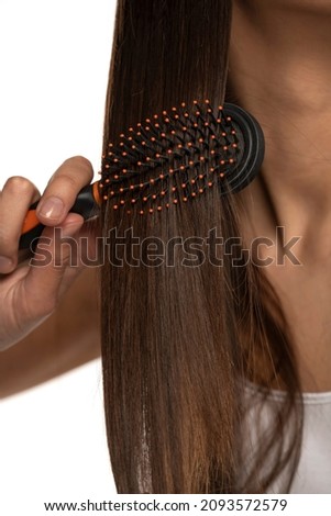 Close up of a young brushing her straight long hair on a white background