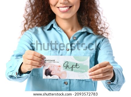 Young African-American woman with gift voucher for massage on white background