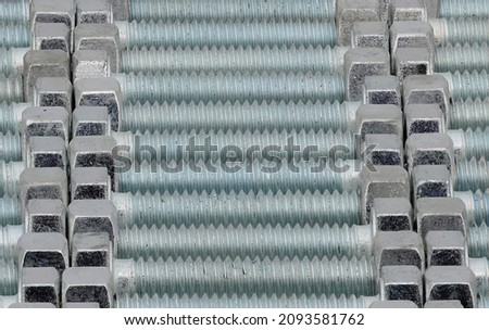 A background of rows of high strength chrome plated bolts with a turquoise sheen, close-up. Royalty-Free Stock Photo #2093581762