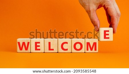 Welcome and support symbol. The concept word Welcome on wooden cubes. Beautiful orange table, orange background, copy space. Businessman hand. Business, welcome and support concept.