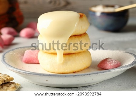 Appetizing syrniki (cottage cheese pancakes), sprinkled with sweet, condensed milk. Delicious and nutritious breakfast. Royalty-Free Stock Photo #2093592784