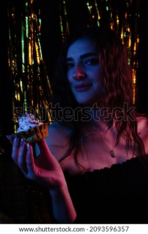 Happy girl holding a cake in her hands on a black and gold background.