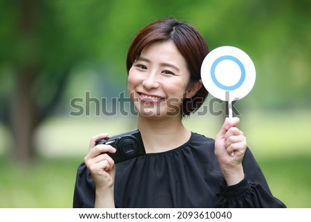 A woman with a compact digital camera and a 〇 tag