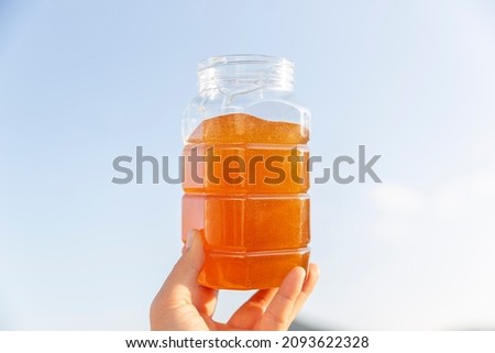 A woman’s hand holding a jar of honey