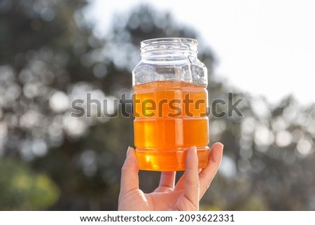 A woman’s hand holding a jar of honey