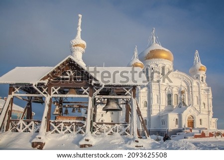 The bells of the Belogorsk Monastery are covered with frost against the background of the White Church.