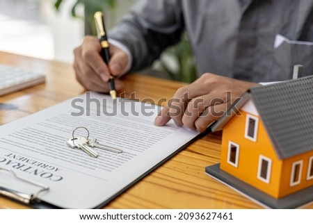 A salesperson of a housing project is drafting a sales contract for a customer who reserves a house in the project he manages. Real estate trading concept.