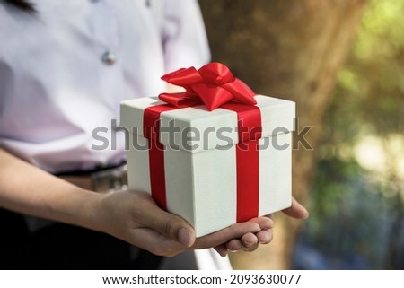 Woman holding gift box with red bow in hand
