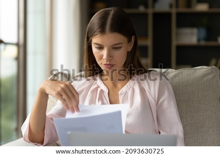Focused student girl receiving letter, checking mail, reading admission notice from school, college. Young homeowner woman doing domestic paperwork, checking paper bills, bank documents Royalty-Free Stock Photo #2093630725