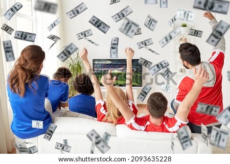 online betting, gambling and sport concept - happy friends or football fans watching soccer on tv and celebrating victory at home over money rain