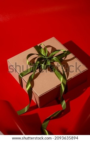 gift box with green ribbon and red background with shadow, selective focus, blurry.