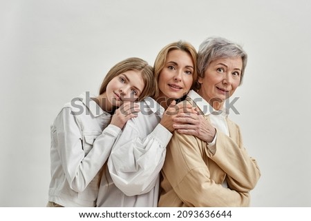 Back to back of caucasian family of three female generations looking at camera. Age and generation concept. Grandmother, mother and granddaughter. Isolated of white background. Studio shoot Royalty-Free Stock Photo #2093636644