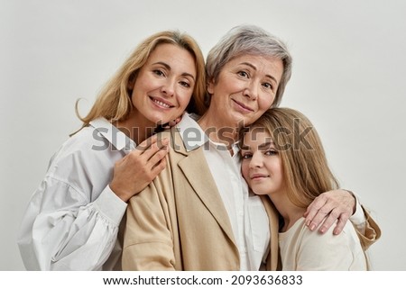 Happy caucasian family of three female generations hugging each other and looking at camera. Age and generation concept. Senior grandmother, adult mother and teenage granddaughter. White background Royalty-Free Stock Photo #2093636833