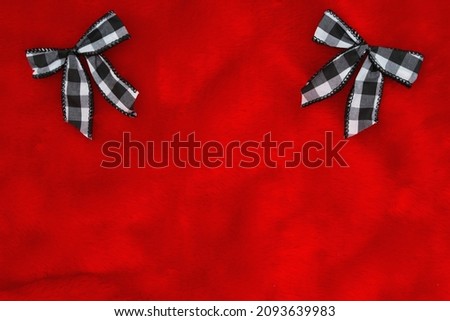 Christmas background with two black and white bows on red plush material with copy space for your Christmas message