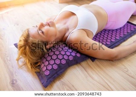 Woman lying on acupressure mat to help balance the body and relieve pain or stress Royalty-Free Stock Photo #2093648743