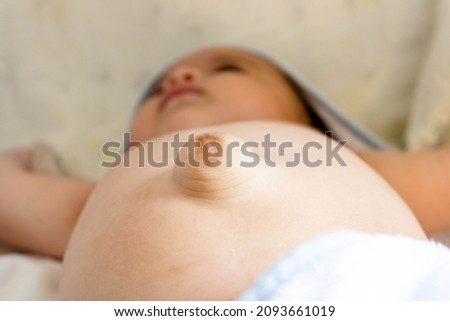 Three month old baby with a very apparent umbilical hernia bouncing out of her belly. Need for medical intervention for resolution. Parental care and precautions with the bowel, digestive system. Royalty-Free Stock Photo #2093661019