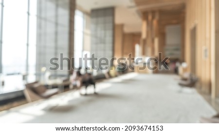Blurred hotel or office building lobby blur background interior view toward reception hall, modern luxury white room space with blurry corridor and building glass wall window Royalty-Free Stock Photo #2093674153