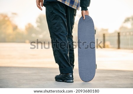 Cropped image of skater holding skateboard on the street. Extreme sports concept