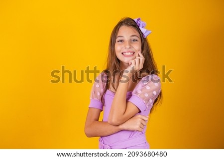 Portrait of a happy smiling child girl in yellow background.