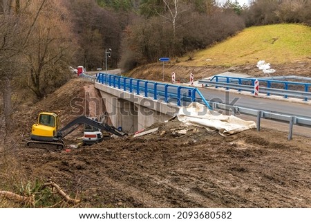 Excavator adjusts the terrain around the new bridge.  Finishing work on the construction of a bridge on a country road in the Czech Republic. 