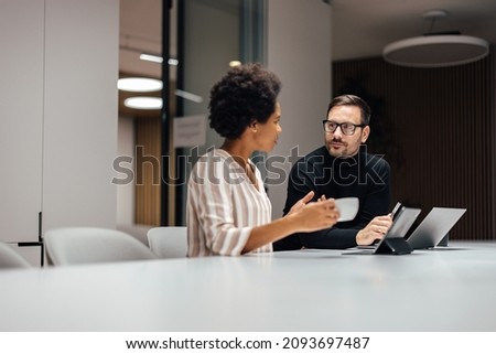 Two diverse employees, taking a breather and talking to each other. Royalty-Free Stock Photo #2093697487