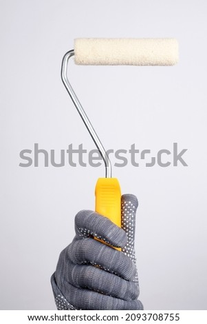 Paint roller on a white background. Hand holds a paint roller on a white background. Paint the walls with a paint roller