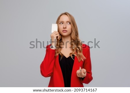 Puzzled and Confused young woman entrepreneur holding credit card, looking troubled, having problem with online order, unable to choose purchase, gray background
