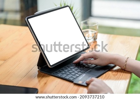 Close up of Woman hand using computer tablet blank white screen and holding credit card shopping online or internet banking on office desk.