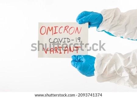 Detail of the arm of a doctor wearing a PPE and latex gloves holding with his hands a sign that reads: 'VARIANTE OMICRON. COVID-19 '. Coronavirus, pandemic and health COncept.