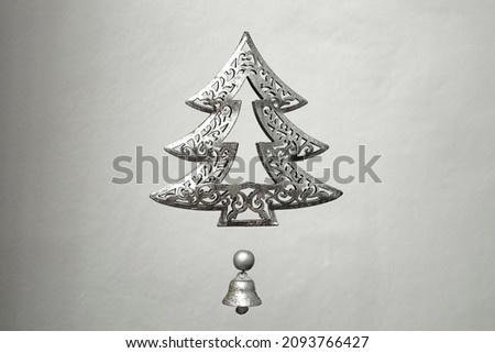 metal christmas tree and little bell, levitating on a grey background
