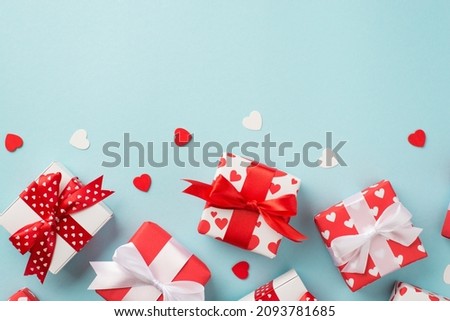 Top view photo of st valentine's day decorations heart shaped confetti a lot of gift boxes in wrapping paper with heart pattern and bows on isolated pastel blue background with blank space