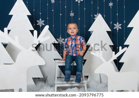 Little blonde and blue-eyed boy surrounded by New Year and Christmas decorations. Celebration of the New Year and Christmas