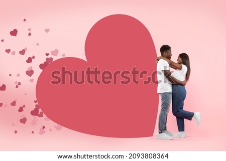 I Love You. Happy black couple hugging standing isolated on pink studio background with red flying hearts and big card heart with mockup free copy space for text or design template. St Valentines Day