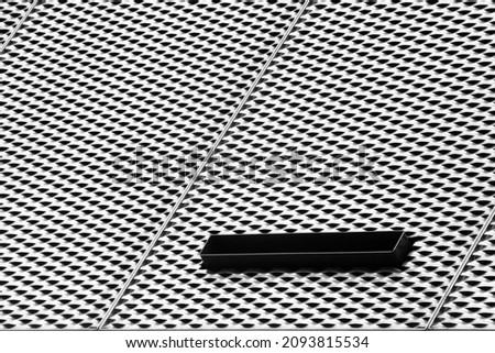 Perforated metal sheets on exterior wall of industrial building. Hi-tech architecture. Decorative steel panels. Technological and material background with black and white geometric pattern.