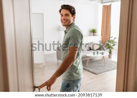 Portrait of excited young man walking in his apartment, entering new home and looking back at camera, happy young guy standing in doorway of modern flat, coming inside, selective focus Royalty-Free Stock Photo #2093817139