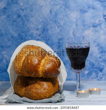 Shabbat Shalom - challah bread, shabbat wine and candles on wooden table on a blue background.