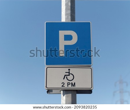 Close-up shot of a handicapped parking sign attached on a pole against a blue sky