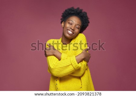 Love yourself, self acceptance. Smiling young african american woman embrace herself, closed eyes. Self-care concept Royalty-Free Stock Photo #2093821378