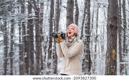 Woman photographer with professional camera. Winter hobby. Enjoy enchanting paleness and freezing atmosphere of winter. Taking stunning winter photos. Enjoy beauty of snow scenery through photos