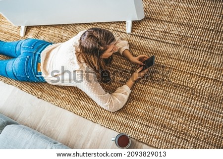 Woman near radiator using smartphone app for temperature control. Pretty woman smiling while using mobile phone to connect with friends at home. Woman Finding A Date Online