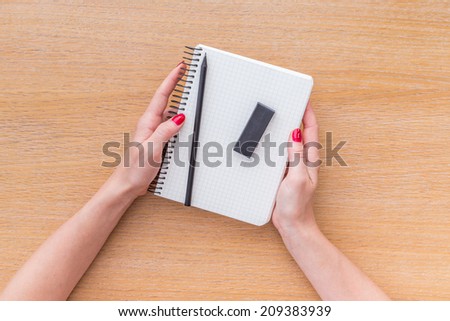 Women hand holding new notebook on wooden background