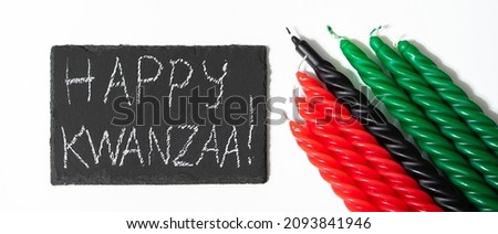 Happy Kwanzaa concept. African-American holiday. Congratulatory lettering and seven candles - red, black and green. African heritage symbol on a white background. Banner format