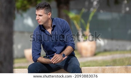 Portrait of a young classy entrepreneur relaxing alone along the Lisbon riverside in Portugal. Classy business man wearing a blue elegant shirt and formal outfit. Successful lifestyle concept. Royalty-Free Stock Photo #2093883076
