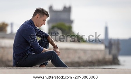 Portrait of a young classy entrepreneur relaxing alone along the Lisbon riverside in Portugal. Classy business man wearing a blue elegant shirt and formal outfit. Successful lifestyle concept. Royalty-Free Stock Photo #2093883088