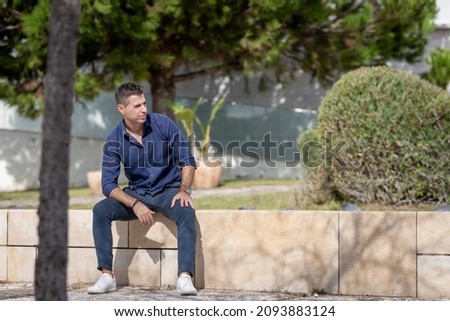 Portrait of a young classy entrepreneur relaxing alone along the Lisbon riverside in Portugal. Classy business man wearing a blue elegant shirt and formal outfit. Successful lifestyle concept. Royalty-Free Stock Photo #2093883124