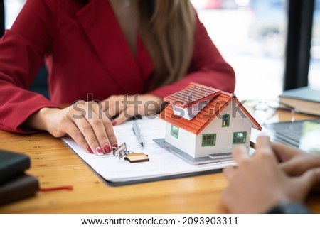 Close up of Business woman giving house key after signing agreement for buying house. Bank manager and real estate concept.