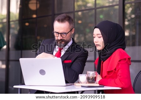 Businessman caucasian and business woman Muslim discussing, consulting, exchanging ideas, analyzing, considering, reasoning about work.