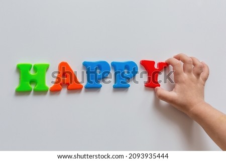 The word HAPPY is composed by a child of colored letters on a white background. Happy childhood.