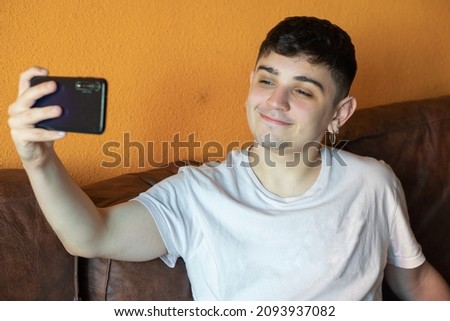 young caucasian man taking a selfie with his smart phone on the sofa