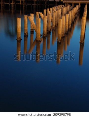 Abstract: long exposure of cement pylons at a dock under artificial lighting.